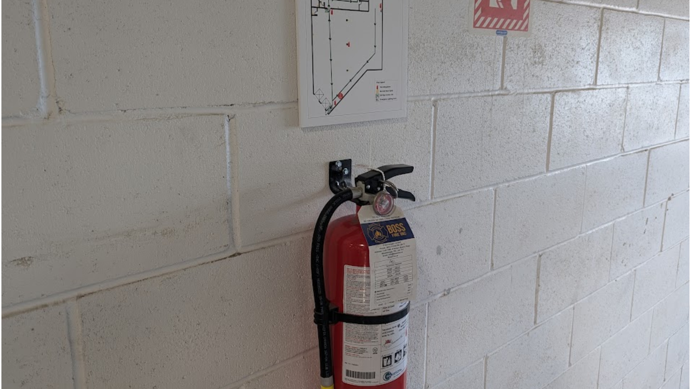Red fire extinguisher mounted on a wall in a commercial workplace